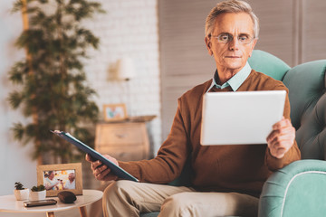 Retired man wearing glasses reading monthly reports