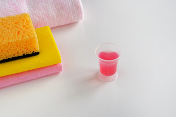 Cleaning concept. Detergent for cleaning room. Measuring plastic cup with pink liquid cleaning agent and cloth wipes. Cleanup housework.