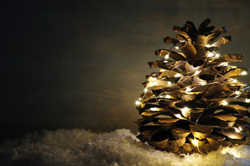illuminated golden pine cone on deco snow