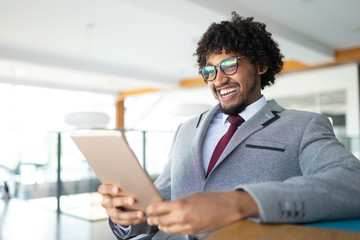 Fototapeta premium Smiling portrait of black businessman with touchscreen tablet device in office