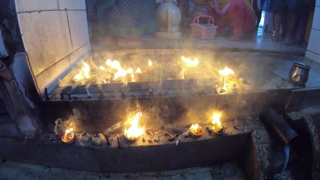 Hands light candles for worship people's legs on background hindu temple timelapse