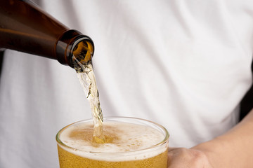 Hands man pouring beer alcohol from bottle into glass