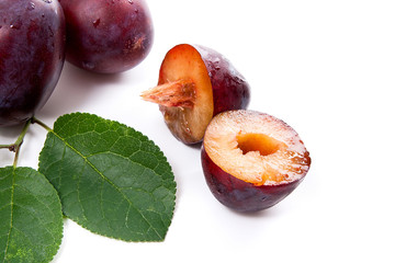 Group of whole and half of ripe plums with leaf isolated on a white background..