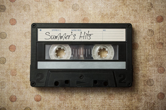 closeup of audio cassette with text "Summer's Hits" on vintage background - Powered by Adobe