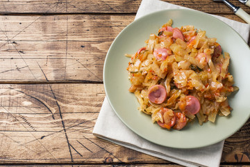 Stewed cabbage with sausages in a plate on the table. Selective focus.