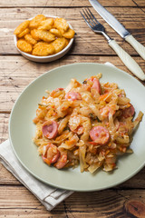 Stewed cabbage with sausages in a plate on the table. Selective focus.