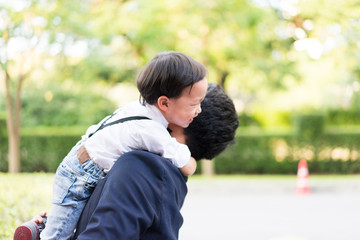 A son hug his father and smile with casual suit in the park.