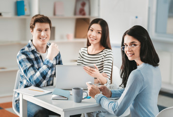 Dark-haired fashion designer wearing glasses working with her team