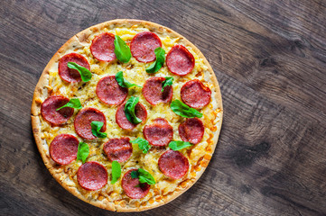 Pepperoni Pizza with Mozzarella cheese, salami, Tomato sauce, pepper, Spices and Fresh Basil. Italian pizza on wooden table background