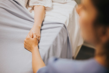 Nurse holding her patients hand