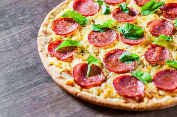 Pepperoni Pizza with Mozzarella cheese, salami, Tomato sauce, pepper, Spices and Fresh Basil. Italian pizza on wooden table background