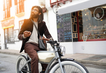 Fototapeta na wymiar Hipster guy with electric vintage style bike using smartphone