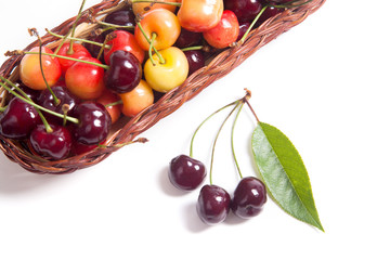 Yellow and red sweet cherry in basket with green leaf isolate on white.