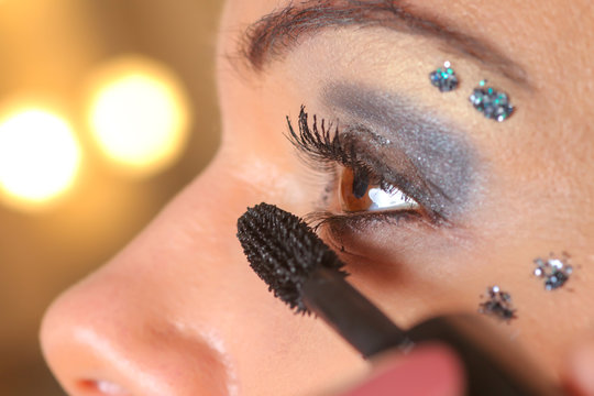 Woman applying mascara on her eyes by brush