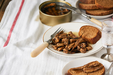 Canned sprats with oil and bread on a plate                              