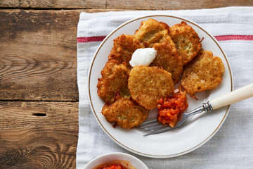 Potato fritters with sour cream and tomato sauce on a wooden table