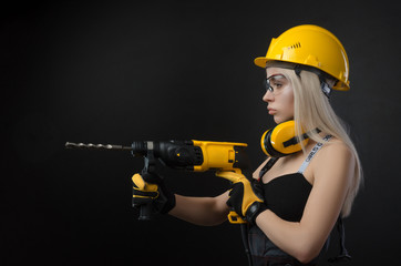 girl in construction clothes and protective equipment posing with a hammer