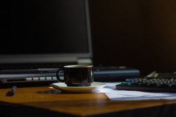 cup on the desktop with a laptop and papers