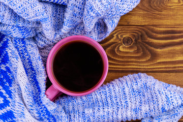 Cup of coffee and cozy knitted sweater on wooden table