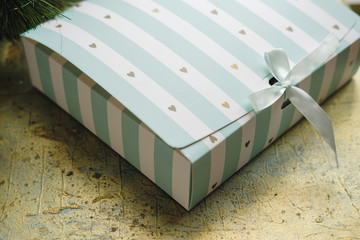 Christmas gift box on golden background. Striped Present. Close up. Copy space