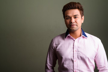 Indian businessman wearing pink shirt against colored background