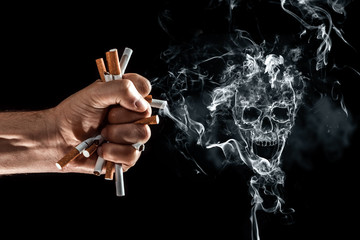 Creative background, male hand clenches a fist of a cigarette. The concept of smoking kills, stop...