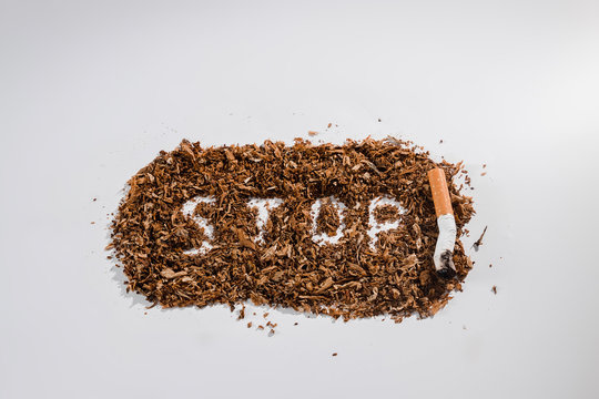 Creative background word stop written in tobacco on white background. The concept of smoking kills, nicatine poisons, cancer from smoking, stop smoking. Copy space.