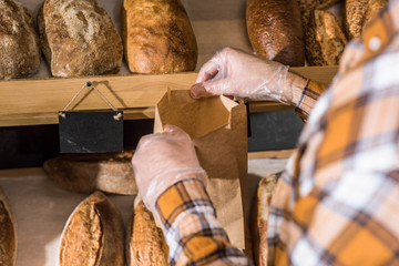 cropped view of male hands putting bread in paper bag