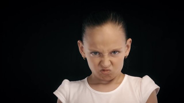 Portrait angry teenager girl clenched fists making kick with leg on black bacground