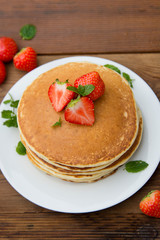 Homemade american pancake with fresh  strawberries, on rustic wooden board. Healthy breakfast. 