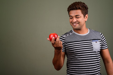 Indian man wearing striped shirt and holding apple fruit