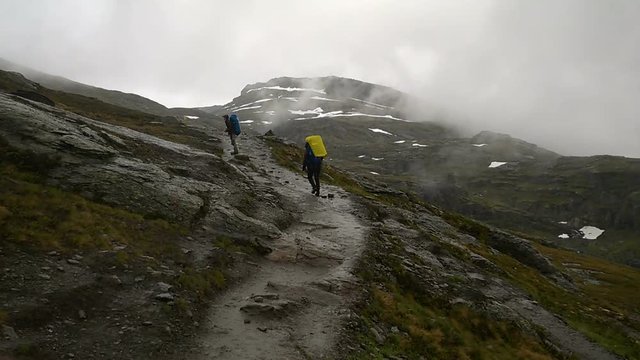 Tourists go on among the rocks. Path to the famous landmark - Trolltunga, Troll tongue. Hiking in Norway.