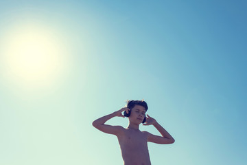 Silhouette of teen boy on the beach in the headphones opposite sun. Traveling on an airplane with children.Concept