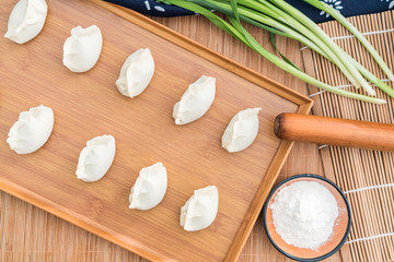 Dumplings, flour, leeks, rolling sticks, on the wooden table