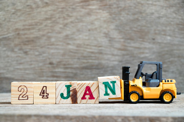 Toy forklift hold block N to complete word 24jan on wood background (Concept for calendar date in 24 month January)