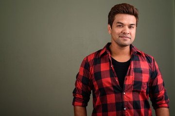Fototapeta premium Indian man wearing red checkered shirt against colored backgroun
