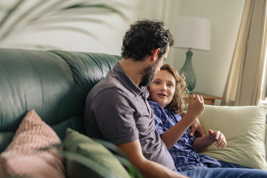 Smiling Father And Young Son Talking Together On Their Sofa