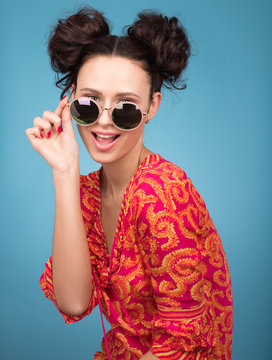 Colorful Studio portrait of beautiful young woman posing in sunglasses. A stylish haircut, bright red blouse