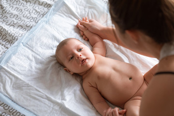 Mother doing massage and gymnastic to her newborn baby hands to reduce muscle tone at home bedroom