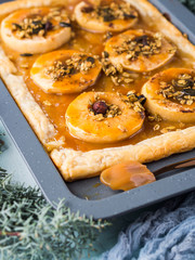 Apple pie on baking tray with caramel and nuts