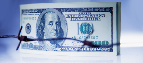 US Dollar money wrapped in barbed wire as symbol of economic warfare, sanctions and embargo busting