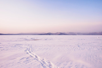 Winter landscape with trails in the snow. A path through the lake. Winter expanses during the twilight. Lake Turgoyak. South Ural. Russia.