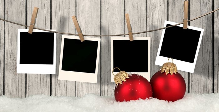 christmas background with instant photos - snow with christmas balls and blank instant photos hanging on the clothesline 