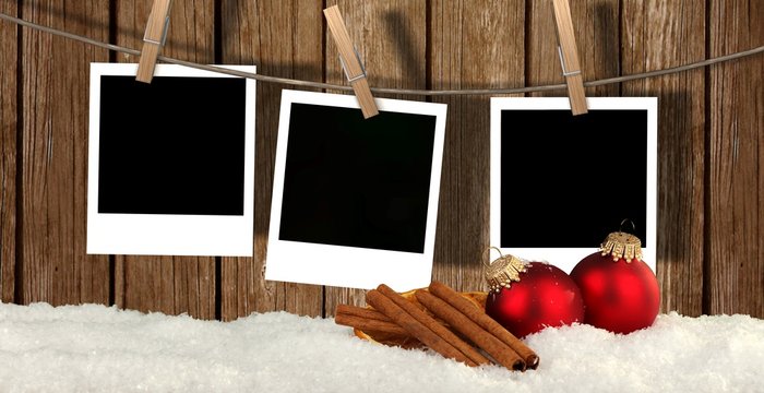 christmas background with instant photos - snow with christmas balls and blank instant photos hanging on the clothesline 