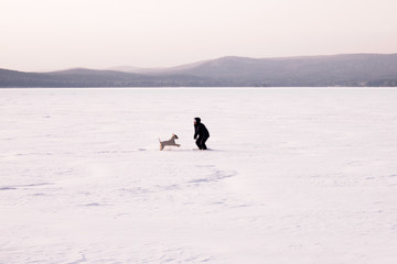 Fototapeta na wymiar Women playing with the dog in the snowly winter. Natural Background. Frozen lake.