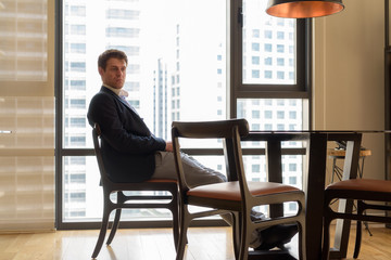 Young handsome businessman sitting in the dining room near the k
