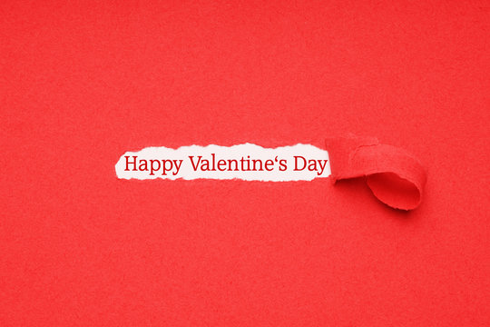happy valentines day greeting text seen through hole ripped in red paper background