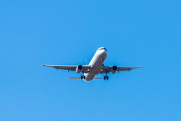 Fototapeta na wymiar A white airplane flying in a clear pale blue sky