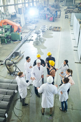 High angle view at  multi-ethnic group of workers standing round senior engineer giving...