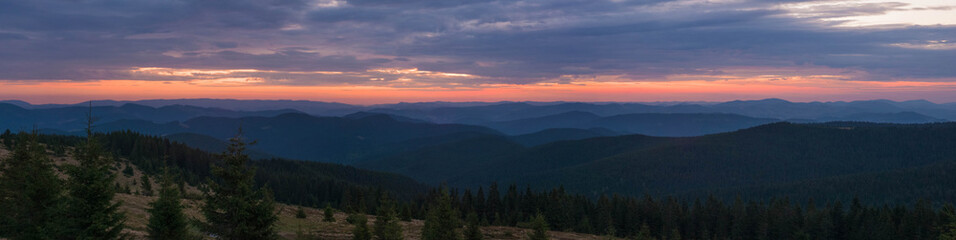 Majestic pink and purple sunrise in the morning in the mountains. Amazing sunrise over Carpathian mountains in the summer. Panoramic morning scene.